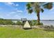 Wooden dock with a boat, green grass and beautiful water views with a tropical palm on a sunny day at 2307 7Th Sw St, Ruskin, FL 33570