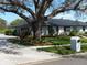 Exterior view of a house with a dark roof, light colored exterior, lush landscaping, and mature trees at 2709 Fairway View Dr, Valrico, FL 33596