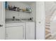 Convenient laundry room with a washer, dryer, storage shelf, and nearby staircase at 325 Madeira Cir, Tierra Verde, FL 33715