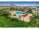 An aerial view of the community pools, landscaping, lounge chairs, and tiki huts on a sunny day at 400 Island Way # 509, Clearwater Beach, FL 33767