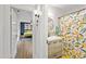 Hallway view of a stylish bathroom with a colorful shower curtain and an adjacent bedroom at 5915 N Otis Ave, Tampa, FL 33604
