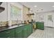 Kitchen with green cabinetry, stainless steel appliances, and exposed brick accent wall at 5915 N Otis Ave, Tampa, FL 33604