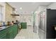 Stylish kitchen featuring green cabinetry, stainless steel appliances, and exposed brick at 5915 N Otis Ave, Tampa, FL 33604