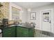 Kitchen with green cabinets, a corner bar, brick accent wall, and modern pendant lights at 5915 N Otis Ave, Tampa, FL 33604