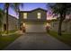 Charming two-story home featuring a well-maintained lawn, a two-car garage, and beautiful sunset sky at 7842 Carriage Pointe Dr, Gibsonton, FL 33534