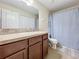 Well-maintained bathroom with wood vanity and countertop featuring a shower with blue curtain at 9873 Trumpet Vine Loop, Trinity, FL 34655