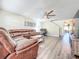 Inviting living room featuring a large leather sectional sofa, ceiling fan, and modern wood-look flooring at 9873 Trumpet Vine Loop, Trinity, FL 34655