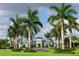 View of the community clubhouse framed by palm trees and lush green lawn at 809 Seascape Pl, Sarasota, FL 34240