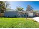 Charming single story home features a well-manicured lawn and a cozy covered porch with blue chairs at 11980 Valencia Ct, Seminole, FL 33772
