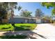 Cozy home with lush green lawn, mature trees, covered porch with blue chairs and a single car garage at 11980 Valencia Ct, Seminole, FL 33772