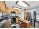 Well-lit kitchen with stainless steel refrigerator, granite countertops, wooden cabinets and center island with wooden floor at 11980 Valencia Ct, Seminole, FL 33772