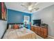 Bedroom featuring a blue accent wall, ceiling fan, and matching wooden dresser with a TV at 1269 80Th N Ave, St Petersburg, FL 33702