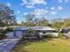 Landscaped single story home featuring a manicured front lawn, driveway, and attached garage at 1269 80Th N Ave, St Petersburg, FL 33702