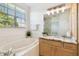 Bright bathroom with a soaking tub, tiled walls, and marble countertop vanity with natural light at 14542 Mirabelle Vista Cir, Tampa, FL 33626