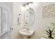 Elegant powder room featuring pedestal sink, decorative mirror, and white wooden wall art at 14542 Mirabelle Vista Cir, Tampa, FL 33626