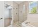 Bathroom features a glass shower enclosure next to soaking tub, and a partial view of bedroom at 14542 Mirabelle Vista Cir, Tampa, FL 33626
