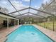 Relaxing screened pool with brick patio, exterior kitchen and landscaped surroundings at 1509 Willow Brook Dr, Palm Harbor, FL 34683