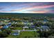 An aerial view of a neighborhood nestled among lush trees, under a vibrant pink sky at 15099 Community Ave, Port Charlotte, FL 33953