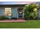 Close-up of a welcoming front door with a wreath, framed by lush tropical plants and manicured landscaping at 15099 Community Ave, Port Charlotte, FL 33953