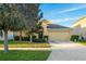 Charming single-story home with a well-manicured lawn, mature trees, and a two-car garage on a sunny day at 15425 Long Cypress Dr, Ruskin, FL 33573