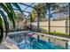 Beautiful pool surrounded by a screened enclosure, showcasing outdoor lounge seating and a serene backyard at 15425 Long Cypress Dr, Ruskin, FL 33573