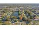 An aerial view of a charming neighborhood with a lake, trees, and a well-maintained home at 1549 San Christopher Dr, Dunedin, FL 34698