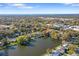 Aerial view of a home with lake and ocean views, surrounded by mature trees in a residential neighborhood at 1549 San Christopher Dr, Dunedin, FL 34698