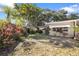 Landscaped backyard featuring tropical plants, a small lawn, and a light colored home with an awning-shaded window at 1549 San Christopher Dr, Dunedin, FL 34698