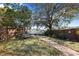Landscaped backyard featuring a swing, stone path, mature trees, and lake view at 1549 San Christopher Dr, Dunedin, FL 34698