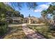 Charming backyard with a brick walkway, manicured lawn, and mature trees at 1549 San Christopher Dr, Dunedin, FL 34698