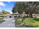 Charming single-story home with mature landscaping and a long concrete driveway at 1549 San Christopher Dr, Dunedin, FL 34698