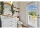 Tastefully decorated powder room with wood shelf, a white vanity and a door to the yard at 501 Washita Stone Dr, Ruskin, FL 33570