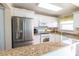 Bright kitchen with stainless steel refrigerator, white cabinets, and granite countertops at 6025 Shore S Blvd # 611, Gulfport, FL 33707