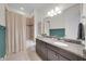 Bathroom featuring granite countertop vanity, large mirror, and shower with neutral tones at 7133 Hatpin Loop, Wesley Chapel, FL 33545