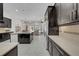 Modern kitchen featuring dark cabinetry, an island with sink, and stainless steel appliances at 7133 Hatpin Loop, Wesley Chapel, FL 33545