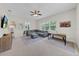 Comfortable living room with a large sectional, ceiling fan, and natural light from large windows at 7133 Hatpin Loop, Wesley Chapel, FL 33545