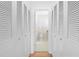 Hallway view into a bright, white bathroom with tiled floor and louvered doors at 7183 Fireside St, Spring Hill, FL 34606