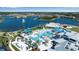 Aerial view of a resort-style pool area with palm trees, cabanas, and a clubhouse overlooking a lake at 8724 Ocean Tides Cv, Parrish, FL 34219