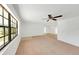Well-lit living room with neutral-toned carpet, ceiling fan, and large windows for ample natural light at 10323 107Th N Ave, Largo, FL 33773