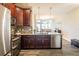 Open-concept kitchen with stainless steel appliances, wood cabinets, granite counters, and modern lighting at 11648 Crowned Sparrow Ln, Tampa, FL 33626