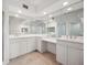 Bright bathroom featuring double sinks, white cabinets, neutral tile, and an abundance of mirror space at 1200 Country Club Dr # 2206, Largo, FL 33771