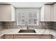 Close up view of remodeled kitchen with a stainless faucet, white cabinets, and marble countertops at 1200 Country Club Dr # 2206, Largo, FL 33771