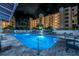 Night view of a well-lit pool and patio area, with palm trees and the condo in the background at 1200 Country Club Dr # 2206, Largo, FL 33771