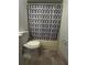 Cozy bathroom featuring a toilet, neutral tile floor, and a shower with a stylish geometric patterned shower curtain at 12155 Environmental Dr # 6, New Port Richey, FL 34654