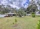 Expansive landscaped backyard featuring mature trees, a large lawn, privacy fence, and tropical foliage at 1216 Lotus Path, Clearwater, FL 33756