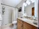 Bathroom featuring a walk-in shower, neutral tile, and wooden vanity with granite countertops at 1216 Lotus Path, Clearwater, FL 33756