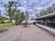 Outdoor brick patio featuring dining table and chairs and view of the screened in patio and tropical landscaping at 1216 Lotus Path, Clearwater, FL 33756