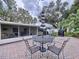 Outdoor brick patio featuring dining table with umbrella, chairs and view of the screened in patio at 1216 Lotus Path, Clearwater, FL 33756