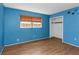 Blue bedroom with wood floors, a closet, and a window overlooking the outdoors at 12704 128Th Ln, Largo, FL 33774