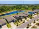 Aerial view of neighborhood pond, homes, and treeline under a blue sky at 14618 Scottburgh Glen Dr, Wimauma, FL 33598